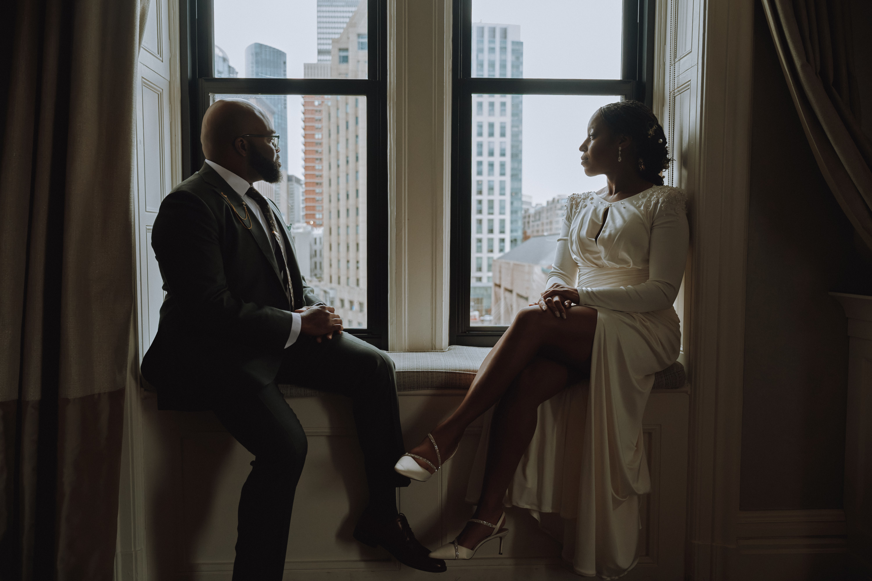 Moody interior wedding portrait of a couple in a classic Boston hotel window